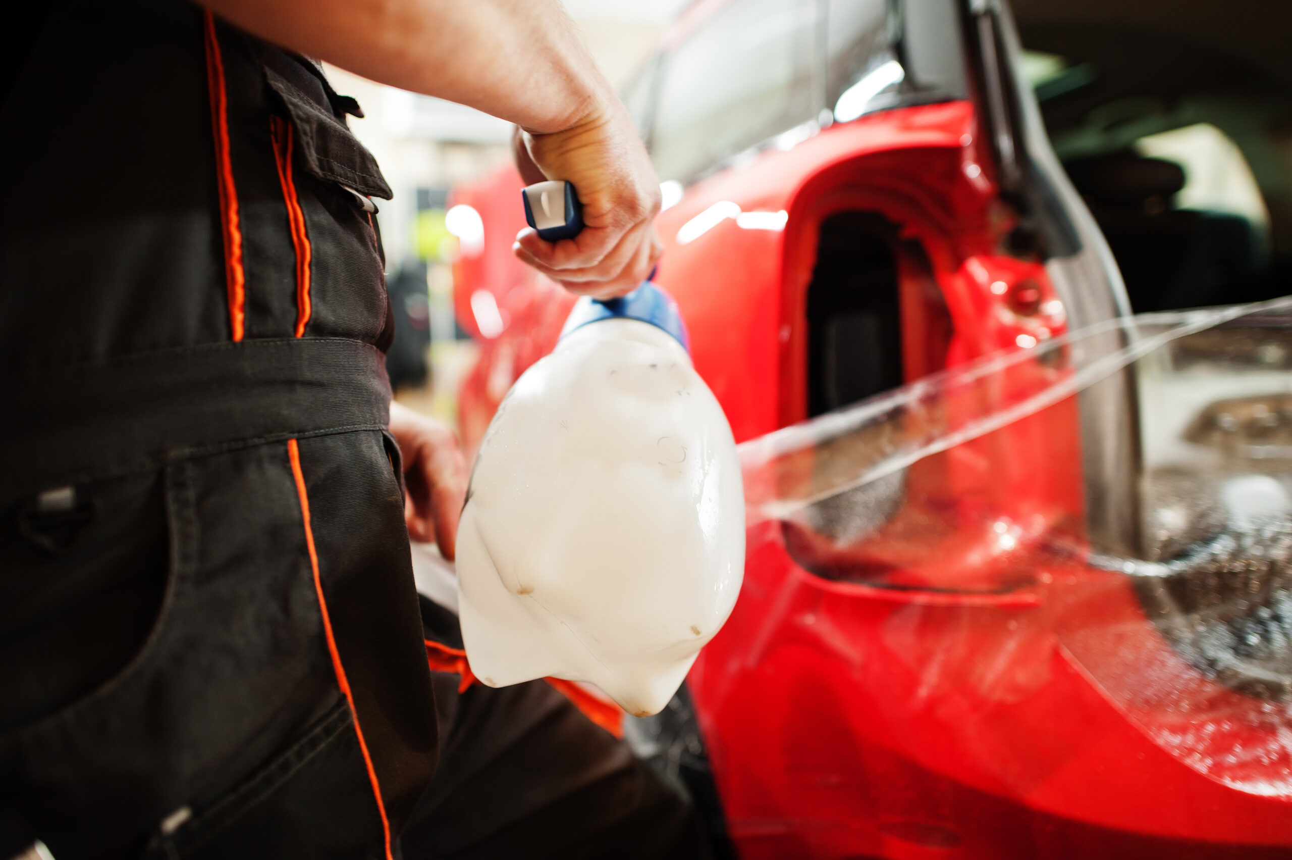 JL Specialties technician applying clear protective film to a red vehicle body panel in West Plains MO