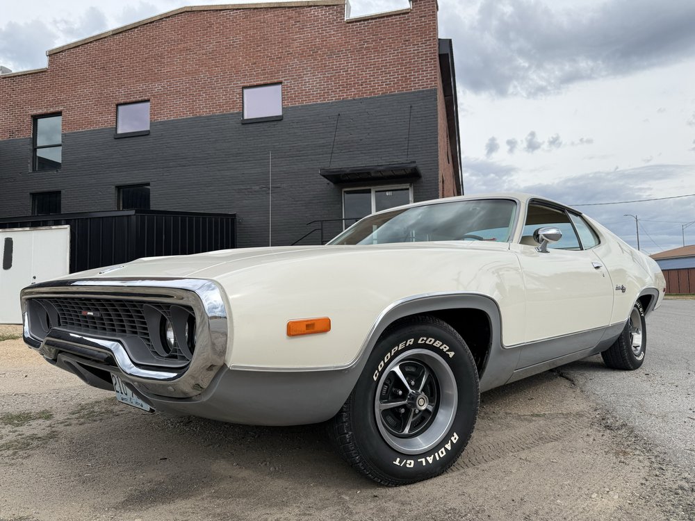 White Plymouth parked outside a brick building