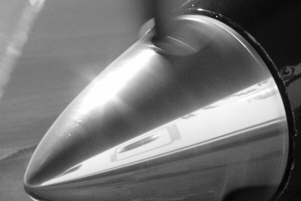 Close-up of polished propeller spinner on light aircraft showing mirror-finish brightwork