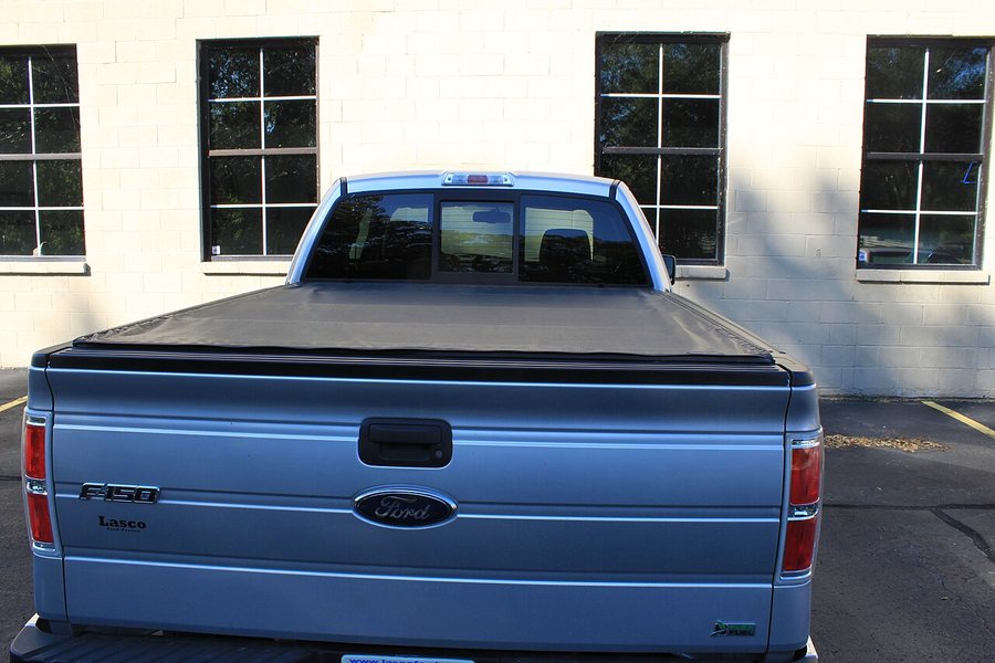 Black tonneau bed cover fitted over a Ford pickup truck bed